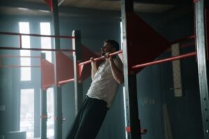 Athlete performs a controlled pull-up on a red horizontal bar