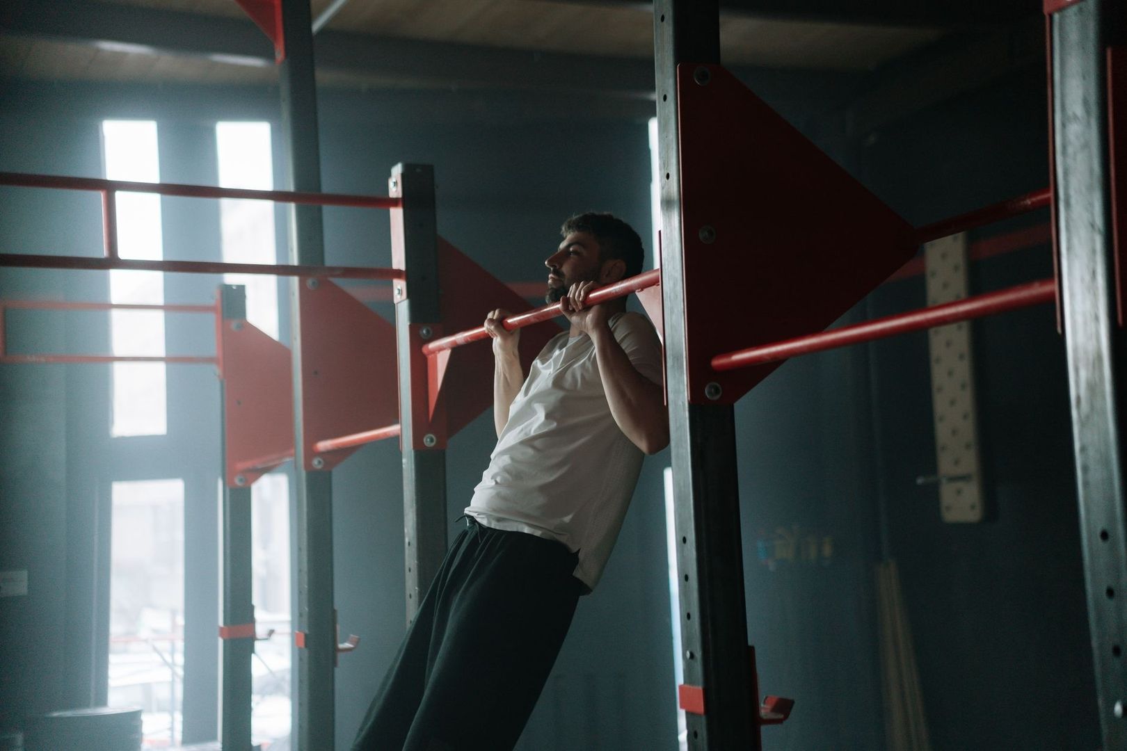 Athlete performs a controlled pull-up on a red horizontal bar