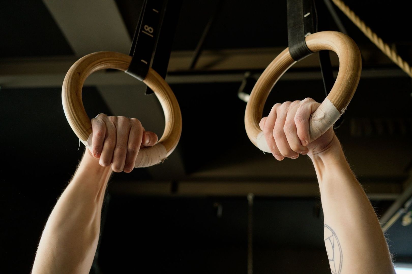 Close-up of taped hands gripping wooden gymnastic rings